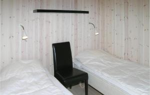 HaslevgårdeにあるAmazing Home In Hadsund With 3 Bedrooms, Sauna And Wifiのベッド2台、椅子、照明が備わる客室です。