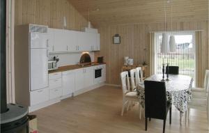 een keuken met een tafel en een witte koelkast bij Cozy Home In Hadsund With Wifi in Haslevgårde
