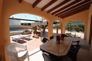 un patio con mesa de madera y sillas blancas en Pineda - modern, well-equipped villa with private pool in Costa Blanca, en Benissa