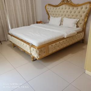 a bed with a gold frame and white sheets at Al Ahmer Apartments in Dubai