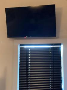 TV de pantalla plana por encima de una ventana con un ciego en Anita, 