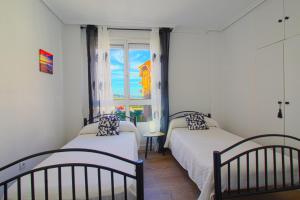 two beds in a room with a window at Entre Playa y Puntal in Somo