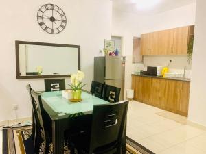 a kitchen with a table with chairs and a clock on the wall at UMAR HOMESTAY - Alanis KLIA in Sepang