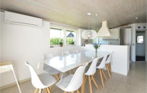 エーベルトフトにあるStunning Home In Ebeltoft With Saunaのキッチン、ダイニングルーム(ガラステーブル、白い椅子付)