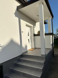 una casa bianca con scale che conducono a una porta bianca di Kuća za odmor Ruža a Nuštar