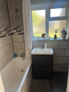 a bathroom with a sink and a tub and a window at Chilled space that sleeps upto 4 in Barking