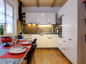 a kitchen with white cabinets and a table with chairs at Apartment Tilia by Interhome in Bönigen +15 photos