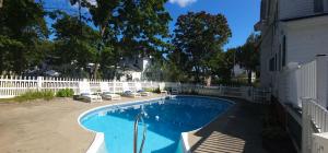 a swimming pool in a yard next to a white fence at Old Orchard Beach Inn in Old Orchard Beach