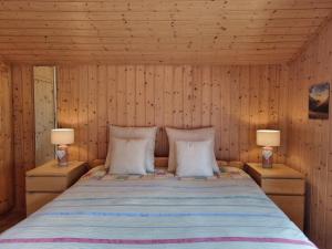 Cama en habitación de madera con 2 lámparas en Holiday Home Le Chant de la Dranse by Interhome, en Sembrancher