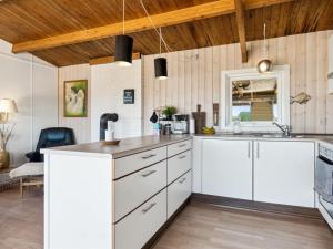 Torsted的住宿－Holiday Home Satu - 500m from the sea in NW Jutland by Interhome，厨房配有白色橱柜和木制天花板。