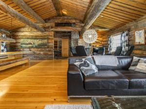 a living room with a black leather couch and wooden ceilings at Holiday Home Villihanhi by Interhome in Kuusamo
