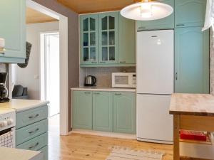 cocina con armarios azules y nevera blanca en Holiday Home Villa vuorso by Interhome, en Raanujärvi