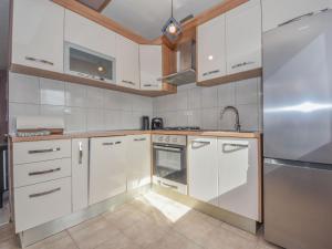 una cocina con armarios blancos y electrodomésticos de acero inoxidable en Holiday Home 4all by Interhome, en Maslenica