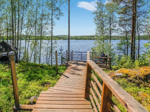 a wooden boardwalk leading to a lake with trees at Holiday Home Aurinkokaari by Interhome in Heinävesi