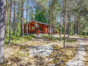 una cabaña de madera en el bosque con un camino de tierra delante en Holiday Home Itälahti by Interhome, en Ihamaniemi