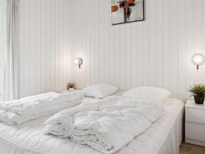 ein großes weißes Bett in einem weißen Zimmer in der Unterkunft Holiday Home Bryngeir - 750m from the sea by Interhome in Brøndstrup