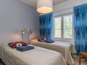- 2 lits dans une chambre dotée de rideaux bleus dans l'établissement Holiday Home Kelotähti a 23 by Interhome, à Saariselka 7 autres photos