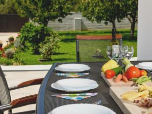 - une table avec des assiettes, des verres à vin et des légumes dans l'établissement Holiday Home Anima by Interhome, à Galovac