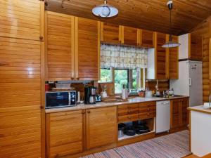 uma cozinha com armários de madeira, um micro-ondas e um fogão em Holiday Home Jyrkänne by Interhome em Pyöli