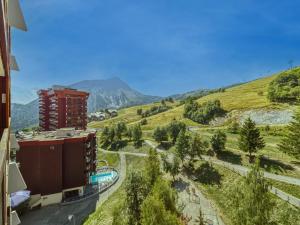 a building on a hill next to a road at Apartment Pegase Phenix-74 by Interhome in Le Corbier