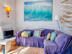 un sofá púrpura en una sala de estar con una pintura en Apartment Duplex Ortal by Interhome en Lacanau