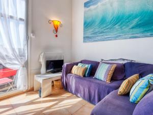 sala de estar con sofá púrpura y TV en Apartment Duplex Ortal by Interhome en Lacanau