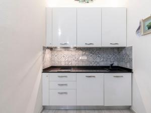 a white kitchen with white cabinets and a sink at Apartment La Santa by Interhome in Imperia