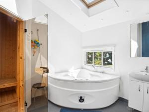 Baño blanco con bañera y lavamanos en Holiday Home Henryk - 350m from the sea in Djursland and Mols by Interhome en Ørby