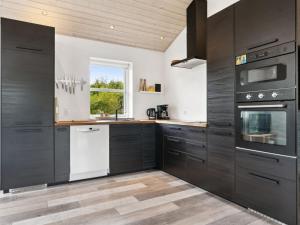 eine Küche mit schwarzen Schränken und weißen Geräten in der Unterkunft Holiday Home Idda - 350m from the sea in NW Jutland by Interhome in Fjerritslev