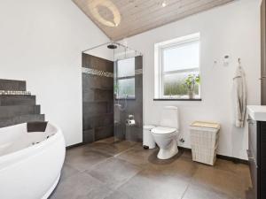 ein Badezimmer mit einer Badewanne, einem WC und einem Waschbecken in der Unterkunft Holiday Home Idda - 350m from the sea in NW Jutland by Interhome in Fjerritslev