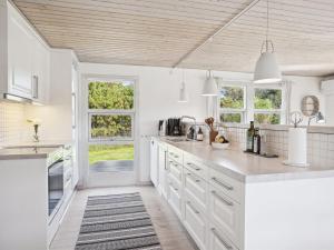 een keuken met witte werkbladen en witte kasten en ramen bij Holiday Home Ofelia - 2-5km from the sea in NW Jutland by Interhome in Blokhus
