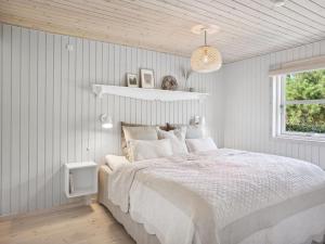 een witte slaapkamer met een bed en een raam bij Holiday Home Ofelia - 2-5km from the sea in NW Jutland by Interhome in Blokhus