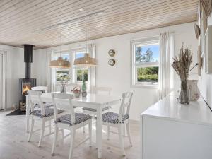een witte eetkamer met een witte tafel en stoelen bij Holiday Home Ofelia - 2-5km from the sea in NW Jutland by Interhome in Blokhus