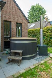 EwijkにあるHoliday Home Forest Cottage Ewijk incl- hot tub by Interhomeの木製ベンチ付きのパティオ
