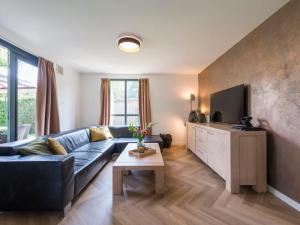 sala de estar con sofá azul y TV en Holiday Home Forest Cottage Ewijk incl- hot tub by Interhome en Ewijk