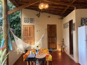 a room with a hammock in a house with a table at Casa Vila Camboinha in Itacaré