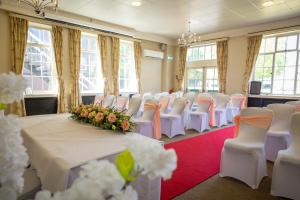 una habitación llena de sillas blancas y una mesa con flores en The Derby Conference Centre and Hotel en Derby