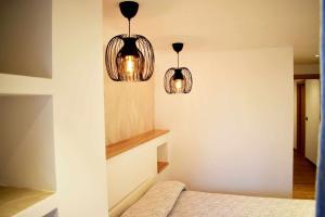 Duas luzes penduradas por cima de uma cama num quarto em Casa Rural Puente Moneo em Garcibuey