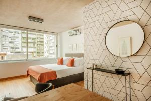 1 dormitorio con cama y espejo en Viví Buenos Aires en este Studio de Diseño #202 en Buenos Aires