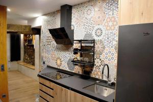 una cocina con fregadero y una pared de mosaico en Casa Rural Puente Moneo, en Garcibuey