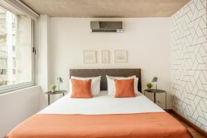 1 dormitorio con 1 cama grande con almohadas de color naranja en Viví Buenos Aires en este Studio de Diseño #202 en Buenos Aires