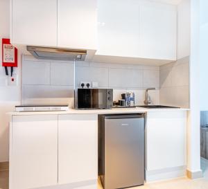 a kitchen with white cabinets and a stainless steel refrigerator at Pyramisa Hotel Apartments in Dubai