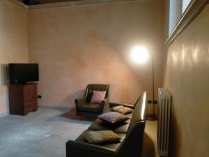 sala de estar con sofá, silla y TV en AL LOFT, Centro Storico en Prato