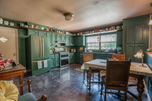 una cocina con armarios verdes y una mesa en Cozy Family-Friendly Getaway, near Austin, en Lockhart