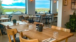 a restaurant with tables and chairs and a large window at Landbrot Guesthouse in Kirkjubæjarklaustur