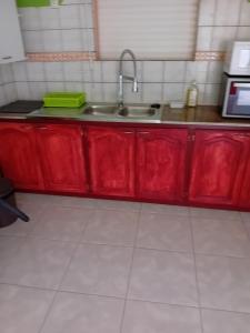 a kitchen with red cabinets and a sink at Résidence Mathurin in Anse-Bertrand