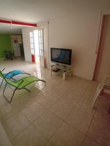 a living room with a television and a tiled floor at Résidence Mathurin in Anse-Bertrand