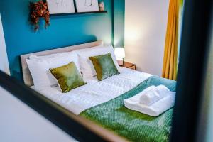 una camera da letto con un letto con lenzuola bianche e cuscini verdi di Spacious 3br close to centre with parking a Knowsthorpe