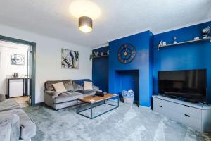 un soggiorno blu con divano e orologio di Spacious 3br close to centre with parking a Knowsthorpe