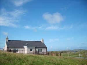 a house on top of a hill with a fence at Harsgeir View Holiday Cottage -Wifi Go green in Breaclete